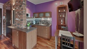 Eine moderne Küche mit Backsteinwand, Holzschränken und einem Essbereich mit Tisch und Stühlen.