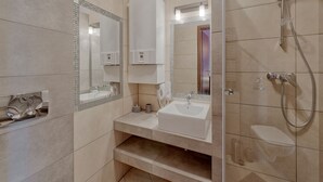 Ein modernes Badezimmer mit einem großen Spiegel, einem Waschbecken und einer Dusche.