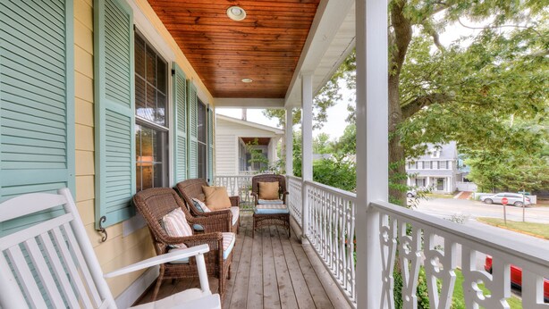A porch with wicker furniture and a white railing.