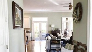 A spacious hallway with hardwood floors, a white door, a framed picture, and a ceiling fan.