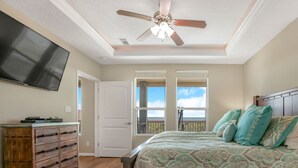 Un dormitorio con cama, ventilador de techo, televisor y cómoda.