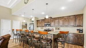 Una cocina amplia con armarios de madera, una isla central con taburetes de bar y un comedor con sillas.