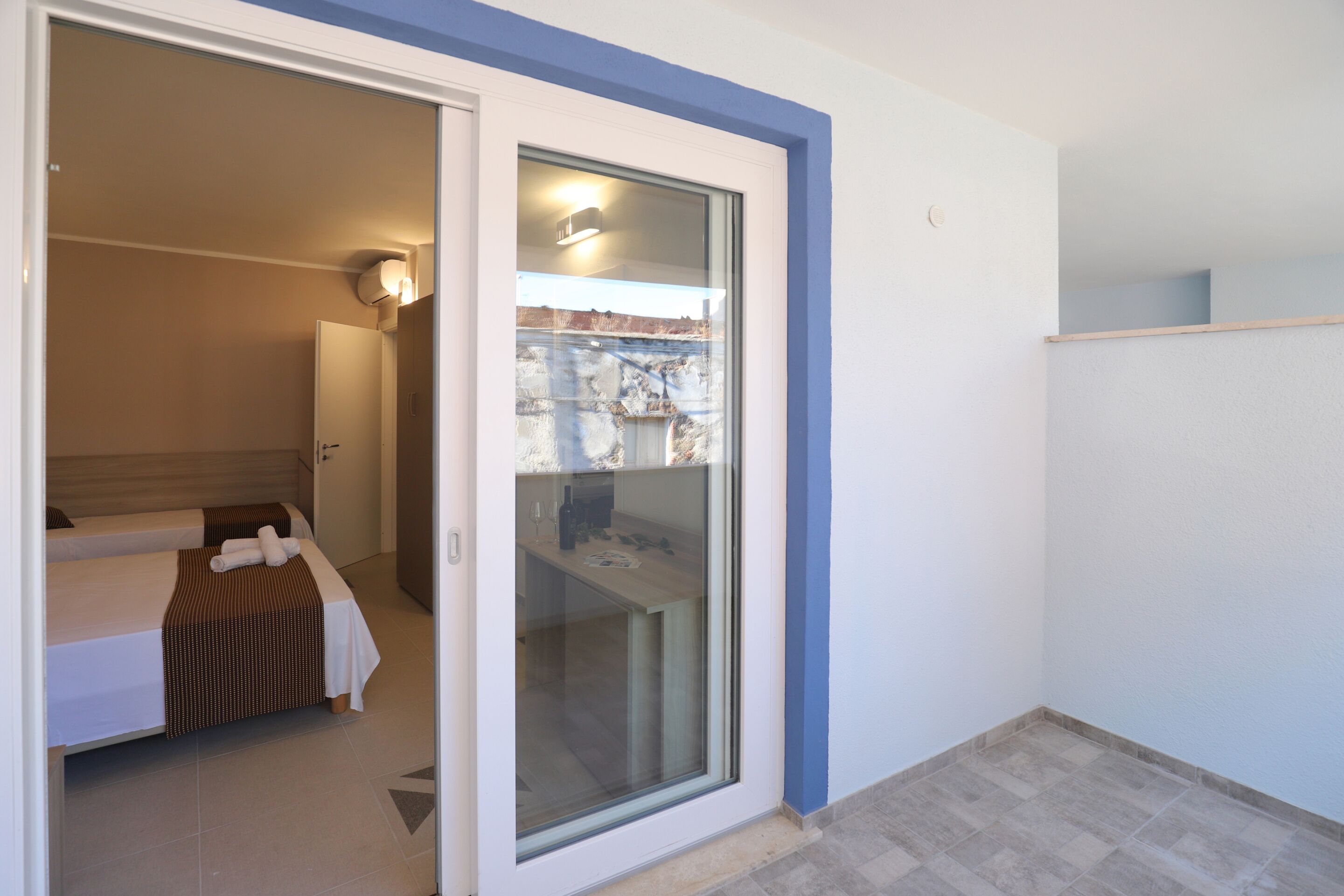 A hotel room with a bed, a bathroom, and a sliding glass door leading to a balcony.