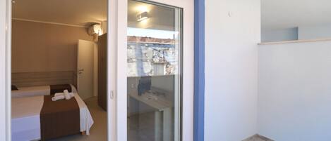 A hotel room with a bed, a bathroom, and a sliding glass door leading to a balcony.