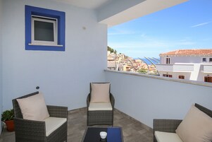 A balcony with wicker chairs, a small table, and a potted plant.