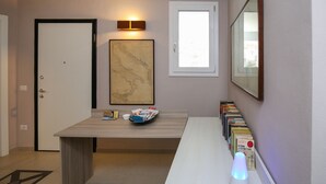 Un passadís amb un escriptori de fusta, un mapa, una estanteria i una porta.