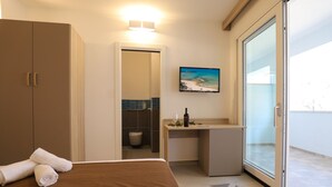 Habitació d'hotel amb llit, escriptori, bany i porta corredissa de vidre a l'exterior.
