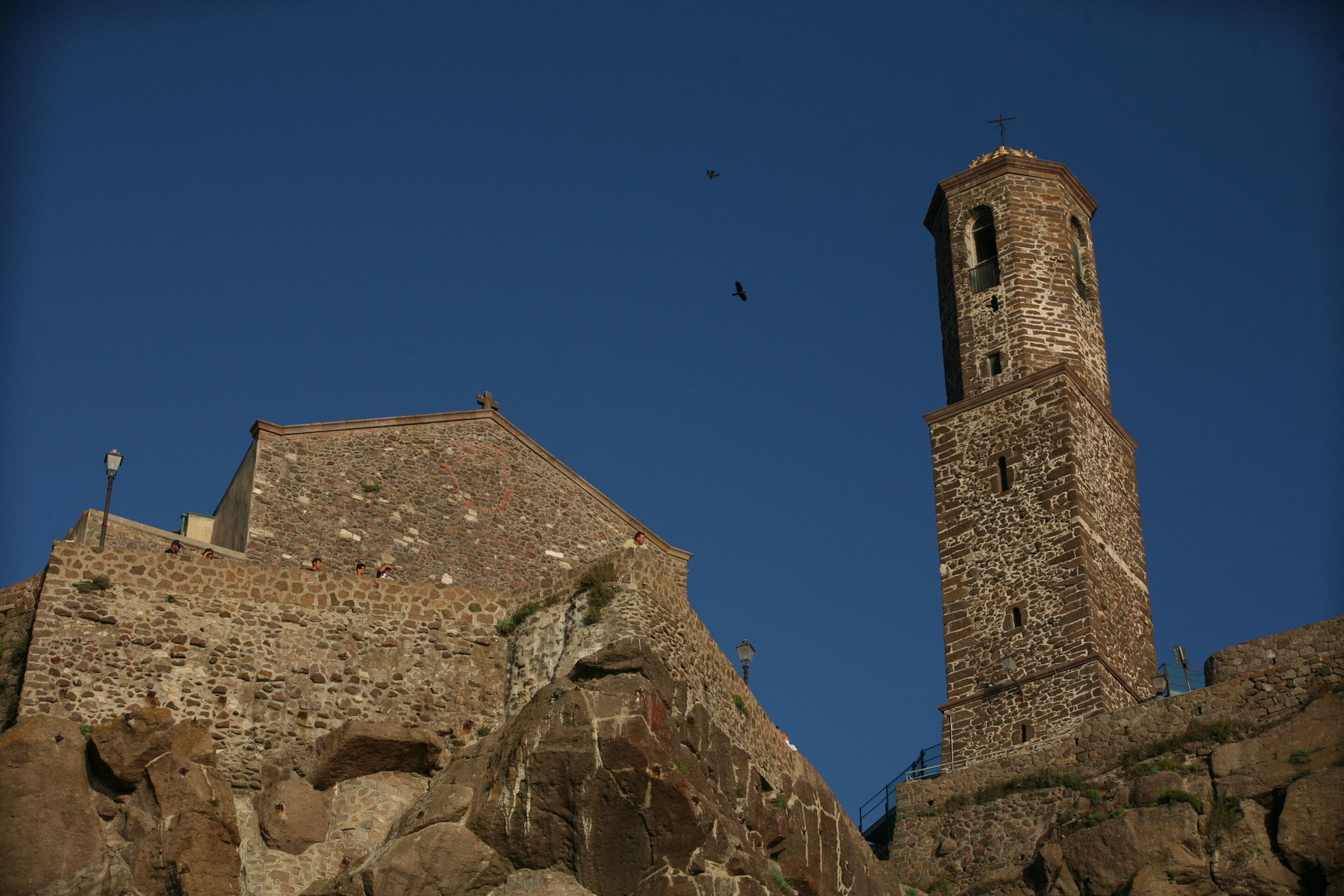 A historic stone building with a prominent tower and a flat-roofed structure.