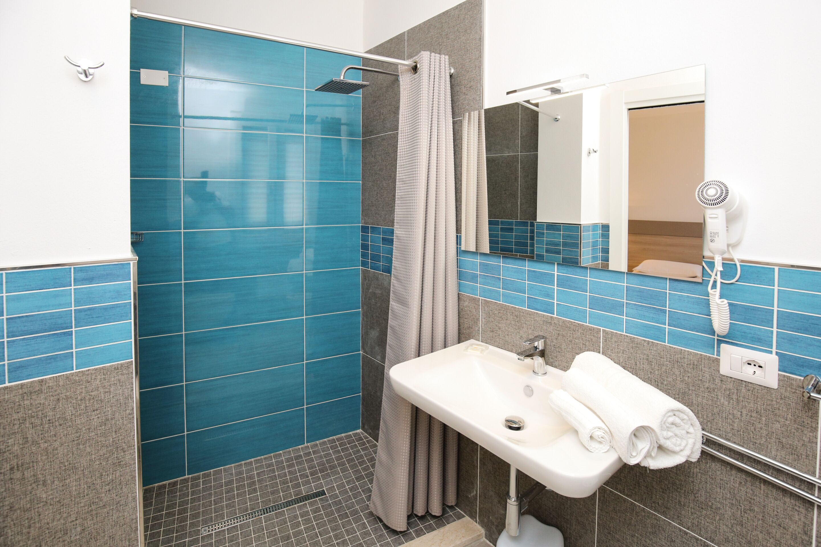Un baño con ducha, lavabo y espejo.