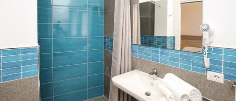 Un baño con ducha, lavabo y espejo.