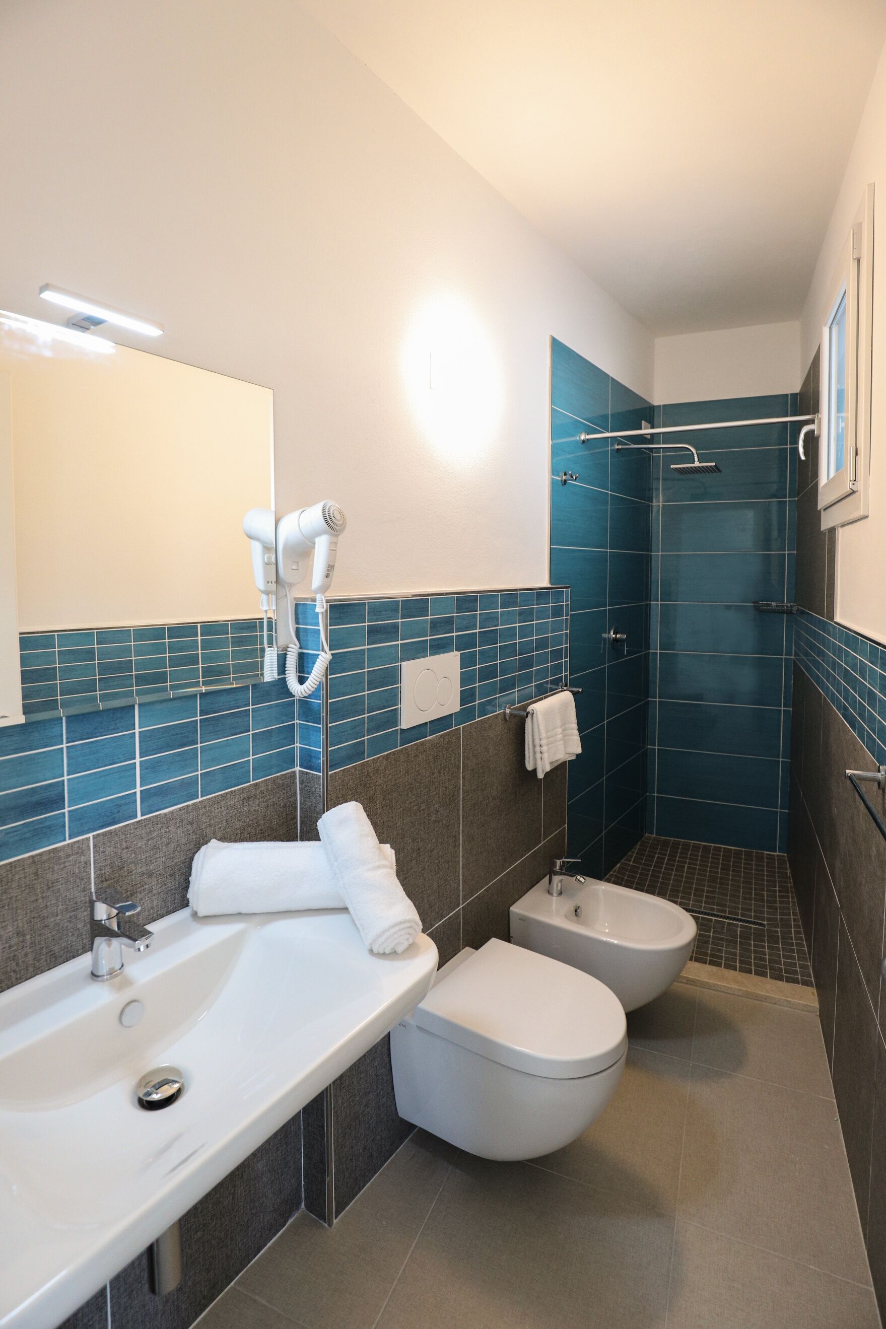 Une salle de bain moderne équipée d’un lavabo, de deux toilettes, d’un bidet et d’une douche.