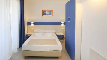 Habitación de hotel con cama, mesitas de noche, armario y un cuadro en la pared.