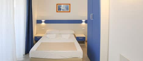 A hotel room with a bed, bedside tables, a wardrobe, and a framed picture on the wall.