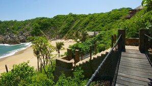 A wooden bridge leading to a beach with a view of the ocean and lush greenery. - Villa Maroma (Santa María Huatulco)