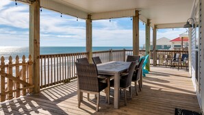 A covered deck with a wooden table and chairs, overlooking the ocean. - Encantado | Cancellation 9/26 week. Pool! (Dauphin Island)
