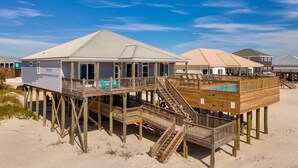 A beachfront property with multiple wooden decks, a pool, and a beach house. - Encantado | Cancellation 9/26 week. Pool! (Dauphin Island)