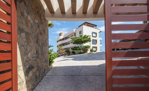 A modern building with a stone facade, a covered walkway, and a clear view of the surrounding area. - Punta Arrocito PH (Santa María Huatulco)