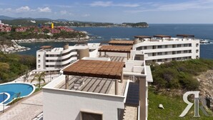 A coastal hotel with multiple buildings, a swimming pool, and a view of the sea and distant hills. - Punta Arrocito PH (Santa María Huatulco)