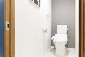 Un baño moderno con inodoro blanco, dispensador de toallas y soporte para papel higiénico.