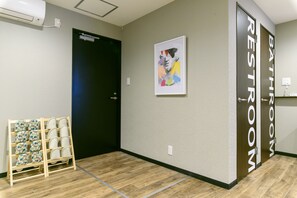 Un baño de hotel con piso de madera, una puerta negra y una obra de arte enmarcada en la pared.