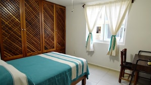 A bedroom with a bed, a wooden wardrobe, a window with curtains, and a chair. - Terrazas C7 (Santa María Huatulco)
