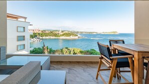 A balcony with a wooden table and chairs, overlooking a coastal view with buildings and a clear sky. - Punta Arrocito B202 (Santa María Huatulco)