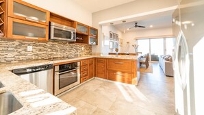 A modern kitchen with wooden cabinets, a built-in microwave, and a dishwasher. - Punta Arrocito B202 (Santa María Huatulco)