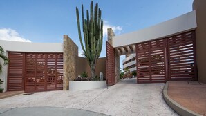 A courtyard with a large cactus, wooden gates, and a modern building facade. - Punta Arrocito B202 (Santa María Huatulco)