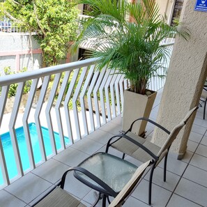 Relax on the balcony with a view of the pool, featuring a glass table and chair.