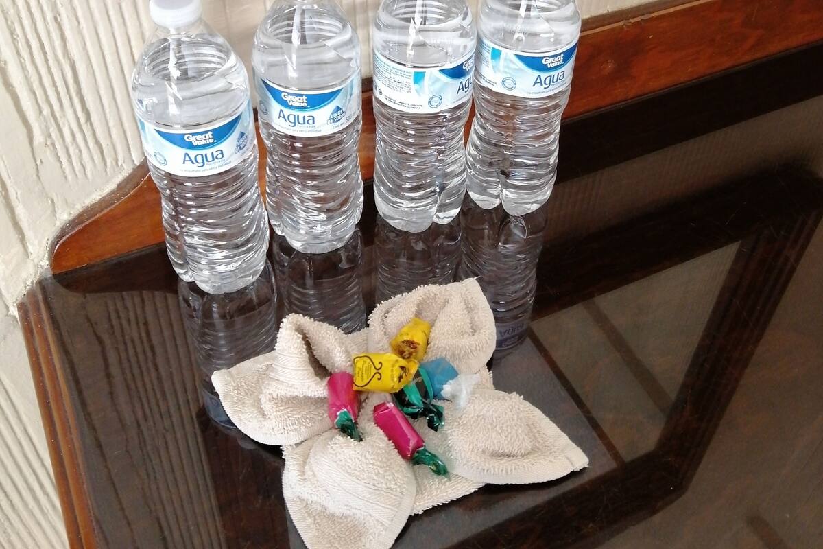 A table with four bottles of Aqua water and a towel with colorful candies.