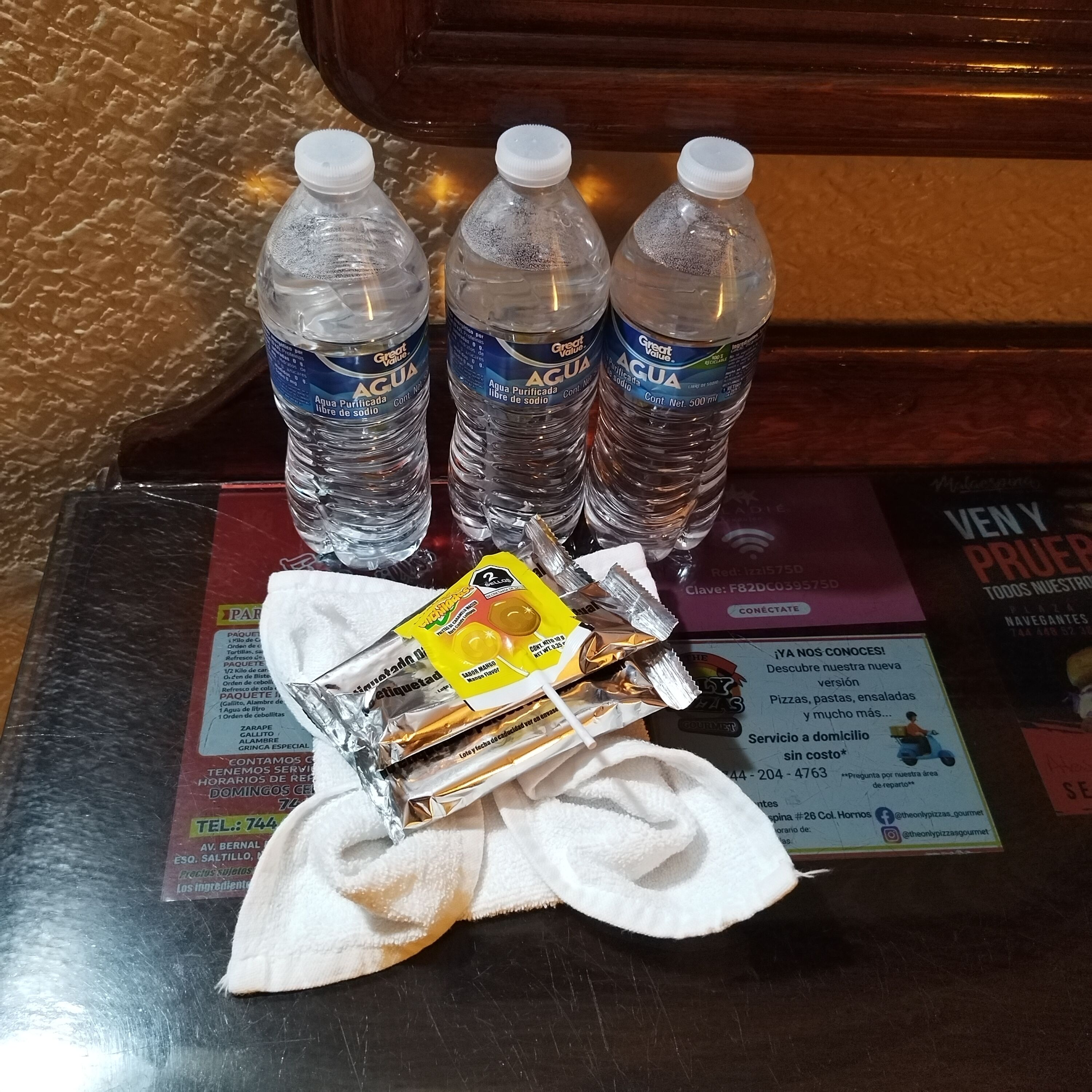 Una mesa con tres botellas de agua, una servilleta y un paquete de aperitivos.