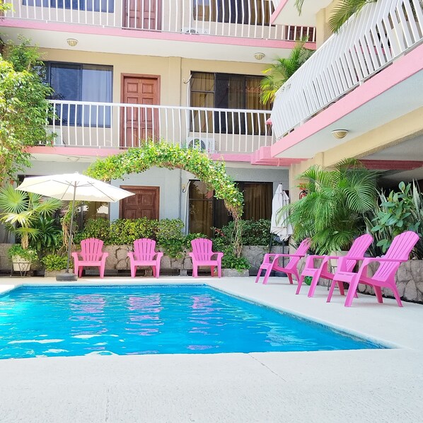 Relax by the pool surrounded by lush greenery and comfortable seating.
