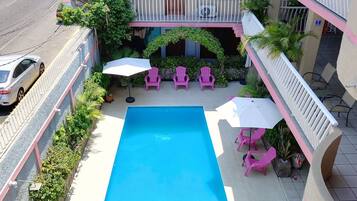 A hotel with a central pool, outdoor seating, and a multi-level balcony.