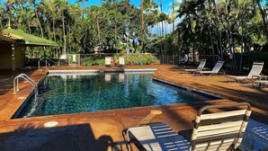 Une piscine avec des chaises longues et des palmiers en arrière-plan.