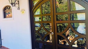 A large, ornate black gate with multiple glass panels, a small window with a decorative sign, and a tiled floor. - Room "El Guayabo" Caroline Bella  (Ajijic)