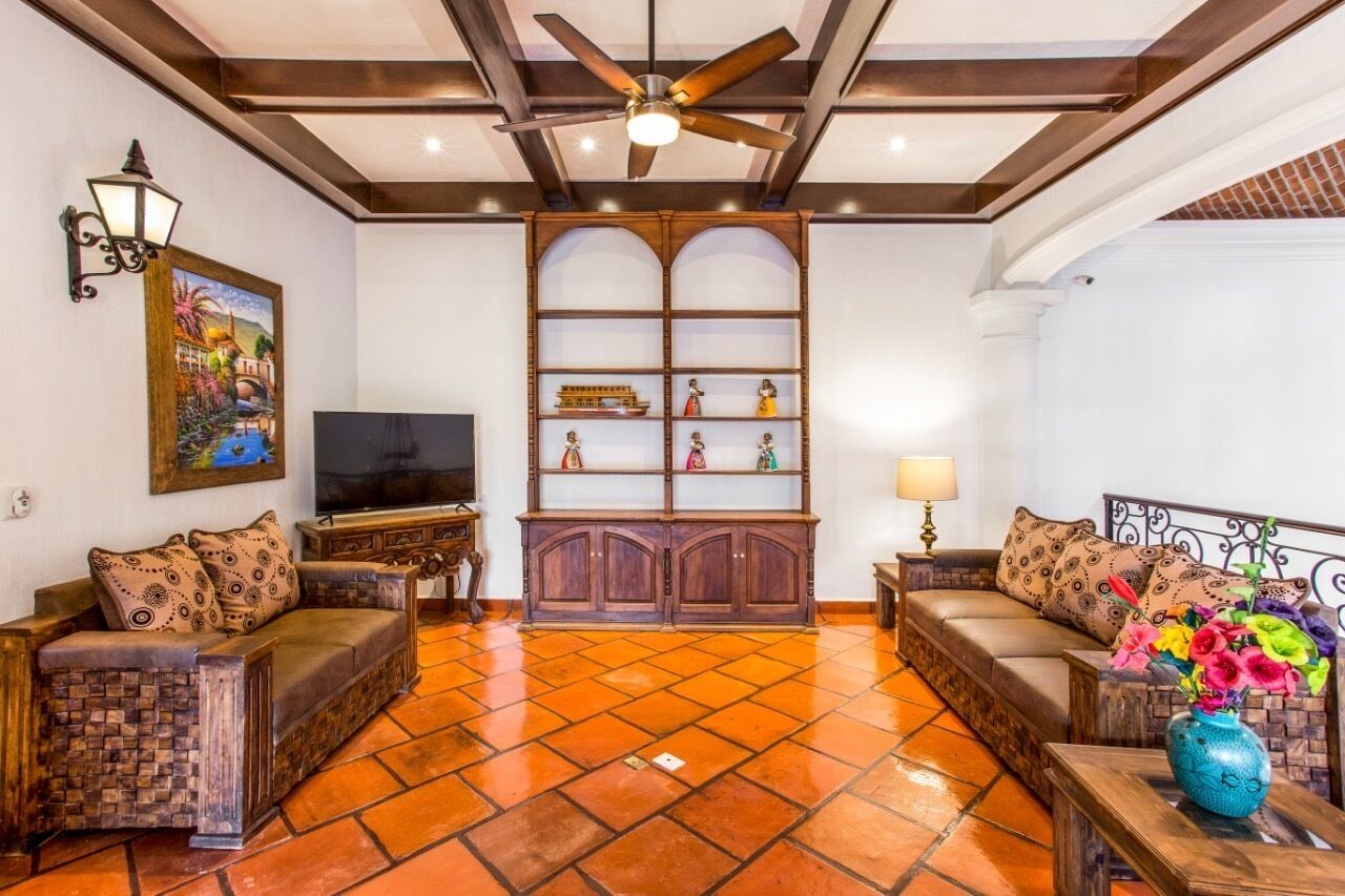 A living room with two sofas, a TV, a wooden cabinet, and a ceiling fan.