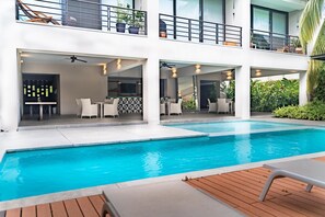 En modern byggnad med en pool, utomhusmöbler och en balkong med växter.