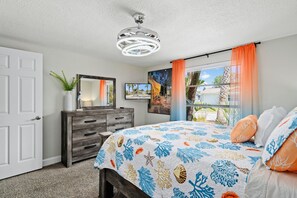 A bedroom with a bed, dresser, and a ceiling fan.
