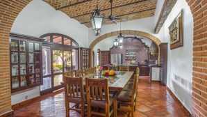 Un comedor amplio con techo de ladrillo, sillas de madera y una mesa grande.