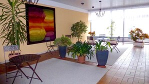 A spacious indoor area with a large abstract painting, multiple potted plants, a dining table with chairs, and a ceiling with recessed lighting. - Apartment 424 with indoor pool (Bad Reichenhall)