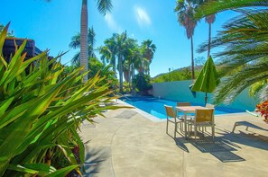 A swimming pool with lounge chairs and umbrellas, surrounded by palm trees and greenery. - Villamar 101 (Santa María Huatulco)