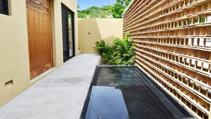 A modern building with a concrete pathway, a wooden door, and a wall with a grid-like structure. - Casa Medina (Santa María Huatulco)