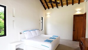 A bedroom with a bed, bedside table, wooden wardrobe, and a window with a view of greenery. - Casa Medina (Santa María Huatulco)