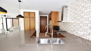 A modern kitchen with a central island, stainless steel appliances, and wooden cabinetry. - Casa Medina (Santa María Huatulco)
