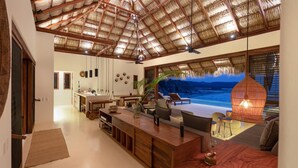 A spacious living area with a large wooden table, comfortable seating, and a view of the ocean.