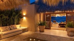 A modern lounge area with a sofa, potted plants, and a view of the ocean.