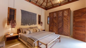 A bedroom with a large bed, wooden wardrobe, and a hanging light fixture.