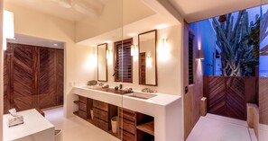Un baño moderno con un espejo grande, tocador de madera y estantes empotrados.