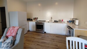 Une cuisine de taille réduite avec des meubles blancs, un four encastré et un four à micro-ondes.