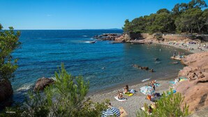 A beach with clear blue water, rocky shore, and people sunbathing. - Appart Abordable pour 4 | Accès Piscine (Saint-Raphaël)